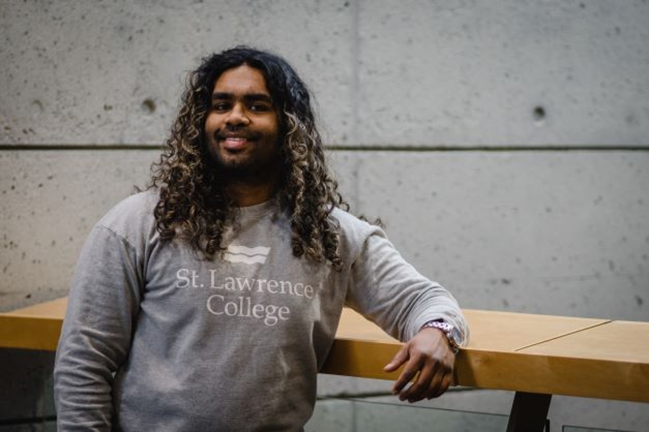 SLC student Sean Ozeer leans against a table in a hallway of the SLC Kingston campus